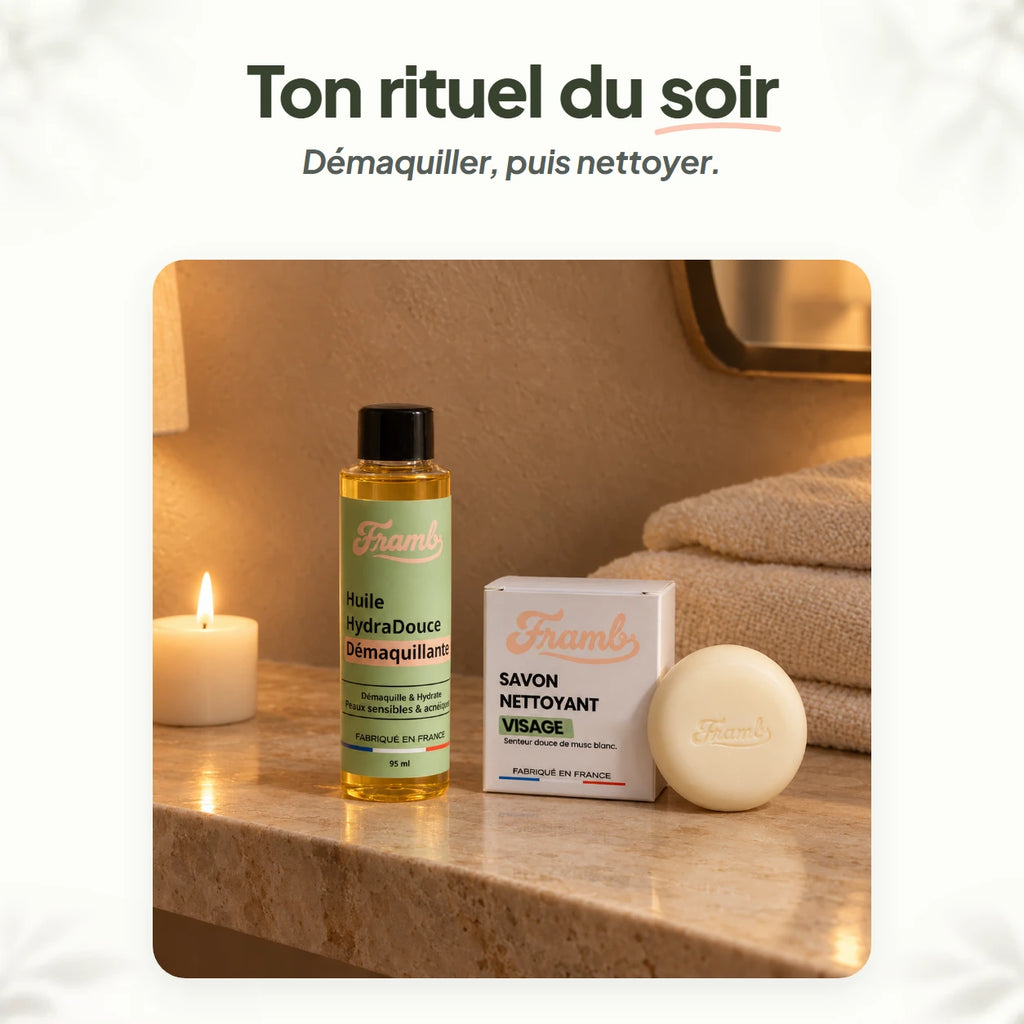 Routine double nettoyage du soir Framb : huile démaquillante et savon sur un plan de salle de bain, à la lumière d'une bougie